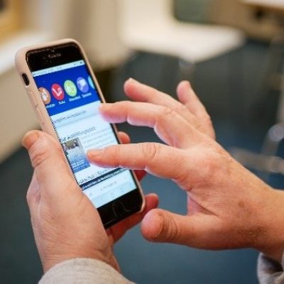 Eine Person, die ein Smartphone zeigt und bedient.